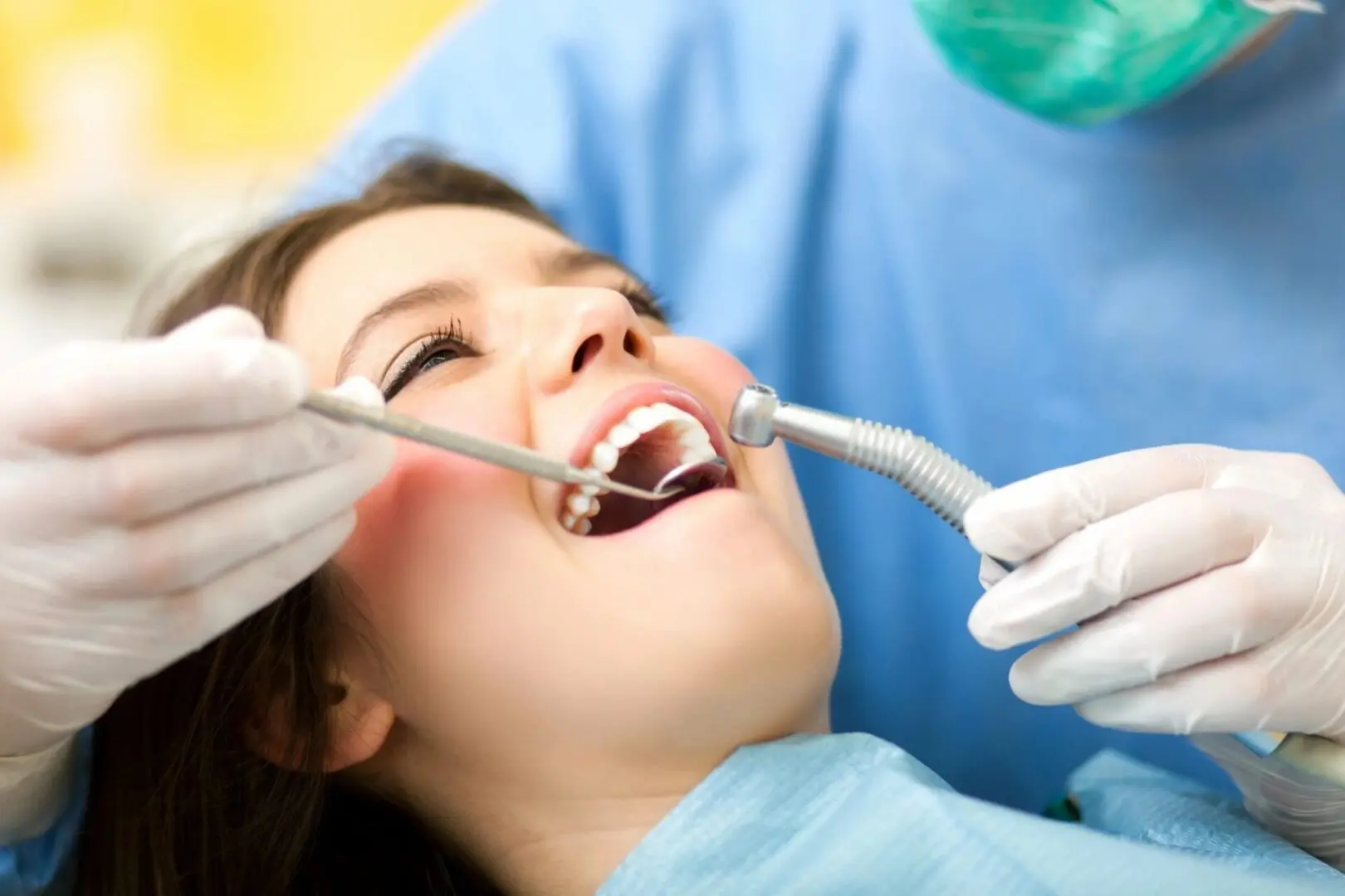 A woman is getting her teeth checked by an dentist.